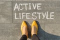 Text active lifestyle written on gray pavement with woman legs, view from above