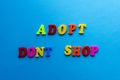 Text adopt don`t shop from plastic colored letters on blue paper background