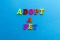 Text adopt a pet from plastic colored letters on blue paper background