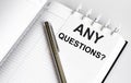 Text ANY QUESTIONS on the short note texture background with pen Royalty Free Stock Photo
