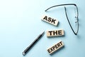 Text ASK THE EXPERT concept on wooden block on the blue background Royalty Free Stock Photo