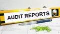 Text Audit Reports on the folder that is located on the financial reports with blue pen and green paper clips