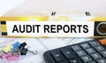 Text Audit Reports on the folder that is located on the financial reports with calculator and stationery clips