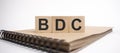 Text bdc on the wooden cubes and craft colored notepad on the white background