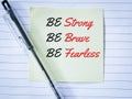 Text be strong, brave and fearless written on sticky note with a pen.