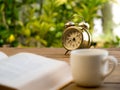 Text book with vintage alarm clock and White coffee cup on the wood table. Royalty Free Stock Photo