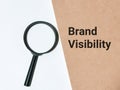 Text brand visibility written on note book with a magnifier.