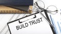 Text BUILD TRUST on Office desk table with notebooks, supplies,analysis chart, on the white background Royalty Free Stock Photo