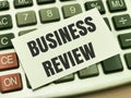 Text BUSINESS REVIEW written on white paper note on calculator.