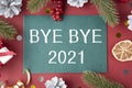 Text Bye Bye 2020 on green paper on red Christmas background. Farewell to 2020 Royalty Free Stock Photo