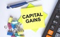 Text Capital Gains on yellow stickers with calculator, blue pen and paper clips