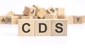 text CDS - Credit Default Swap - is written on three wooden cubes standing on a white table. in the background - a