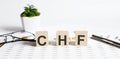 Text of CHF on the wooden cubes on chart with pen and glasses Royalty Free Stock Photo