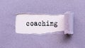 Text COACHING on the white background under violet torn paper