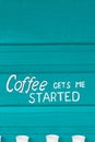 Text Coffee gets me started on a wooden turquoise background.