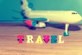 Text in colored letters - travel, on the background of a toy airplane, photo with summer tint