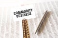 Text COMMODITY BUSINESS on paper card, pen, financial documentation on table