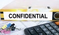 Text Confidential on the folder that is located on the financial reports with calculator and stationery clips
