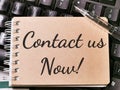 Text CONTACT US NOW written on brown paper note on computer keyboard. Royalty Free Stock Photo