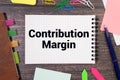 Text CONTRIBUTION MARGIN on Notebook and office tools on the gray desktop