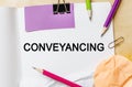 Text Conveyancing on a white note background with pencils, stickers and paper clips. Business concept