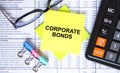 Text Corporate Bonds on yellow stickers with calculator, eyeglasses and paper clips