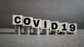 text covid-19 written on wooden blocks concept with downward stack of coins