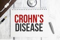 The text CROHN DISEASE on a notebook on a white table next to a stethoscope