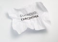 Text on the crumpled paper `diagnosis - carcinoma` as a notification of the disease
