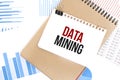 Text DATA MINING on white paper sheet and brown paper notepad on the table with diagram. Business concept Royalty Free Stock Photo