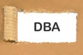 text DBA on white paper under a torn piece of cardboard