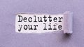 The text DECLUTTER YOUR LIFE appears on torn lilac paper against a white background