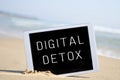 Text digital detox in a tablet computer, in the sand of a beach