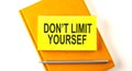 Text DON`T LIMIT YOURSELF on the sticker on the yellow notebook