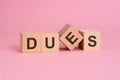 text dues on wooden cubes on pink table