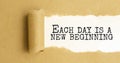 Text Each day is a new beginning appearing behind ripped brown paper