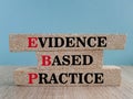 Text EBP Evidence-based practice concept on brick blocks. Beautiful blue background, wooden table.