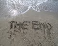 Text THE END written on the sand and the wave that is deleting t Royalty Free Stock Photo