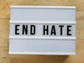 Text in english spelling `End Hate` on a lightbox against wood  background Royalty Free Stock Photo