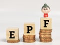 Text EPF on wooden cubes with stacked coins and miniature old woman.EPF stands for Employee Provided Fund. Royalty Free Stock Photo