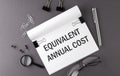 Text EQUIVALENT ANNUAL COST on Notebook and office tools on gray desktop Royalty Free Stock Photo