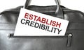 Text ESTABLISH CREDIBILITY writing on white paper sheet in the black business bag. Business concept