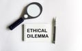 Text Ethical Dilemma on notepad, magnifier and pen, business concept