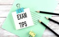 Text EXAM TIPS on the short note with pencils on the wooden background