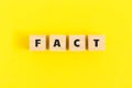 Text FACT on wooden cubes on yellow