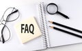 Text FAQ on the sticker with keyboard , pencils and office tools Royalty Free Stock Photo