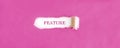 The text FEATURE appearing behind torn pink paper