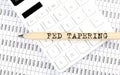 Text FED TAPERING on the wooden pencil on calculator with chart