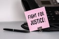 The text Fight for Justice written on a pink sticky note to remind you an important event. Closeup of a personal agenda