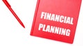 The text FINANCIAL PLANNING is written on a red notepad near a red pen on a white table in the office. Business concept Royalty Free Stock Photo